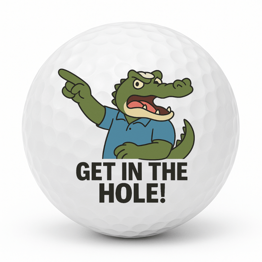 Cartoon crocodile golfer pointing and shouting with the text Get In The Hole on a white golf ball.